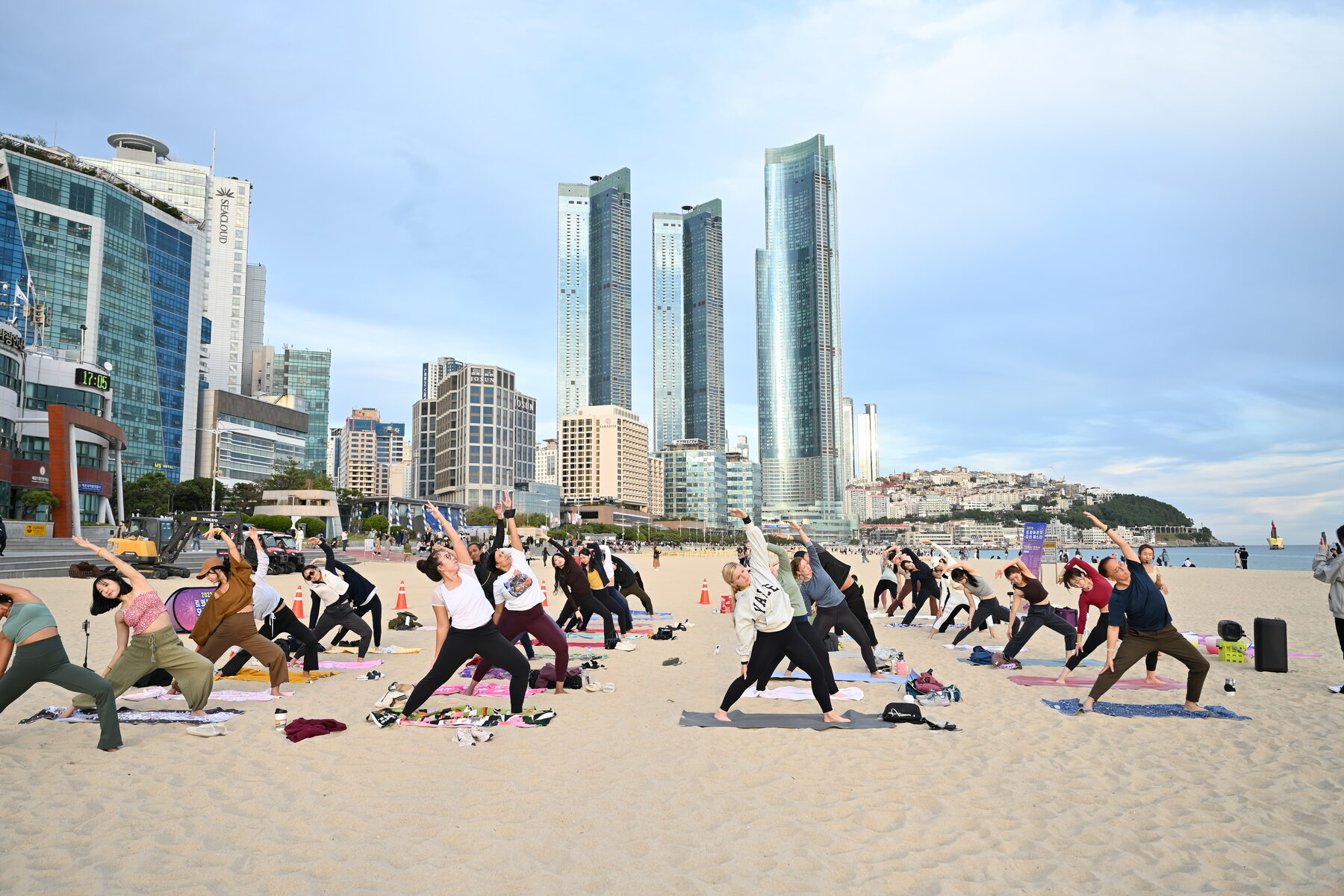 A WellMi beach yoga class at Haeundae, Busan's high-rise skyline behind the group