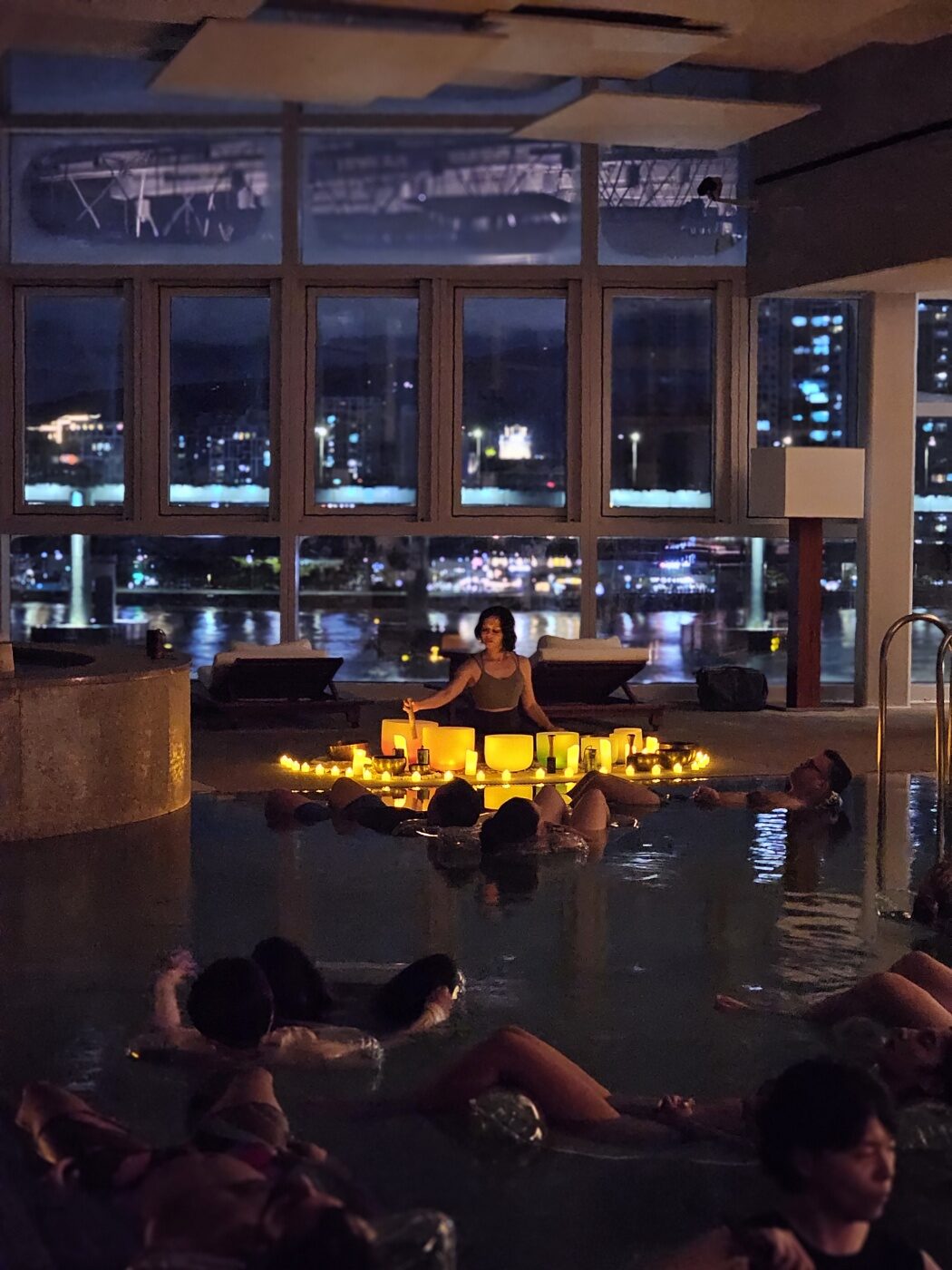 A candlelit WellMi sound bath held in a rooftop pool at night